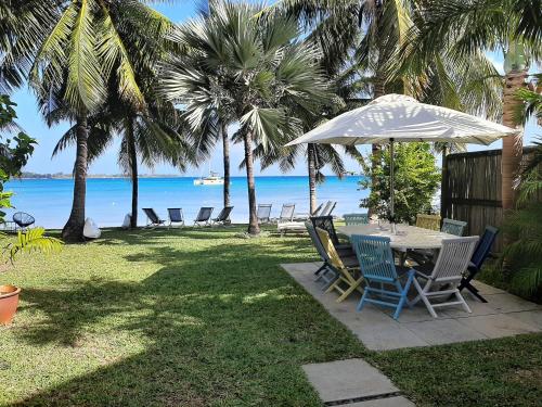 a table with chairs and an umbrella on the beach at Fantastic spacious beachfront VILLAVACANCES in Grand Baie