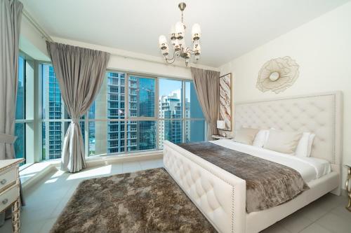 sypialnia z dużym białym łóżkiem i dużymi oknami w obiekcie HiGuests - Dazzling Apt With Panoramic View Near Burj Khalifa w Dubaju