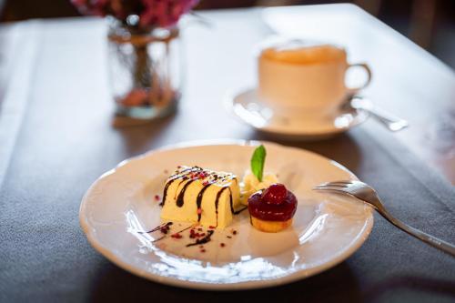 a plate of dessert on a table with a cup of coffee at Wohlfühlhotel Frohsinn in Fischen