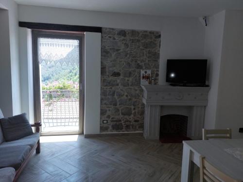 a living room with a fireplace and a large window at B&B CasaCaselle in Caselle in Pittari