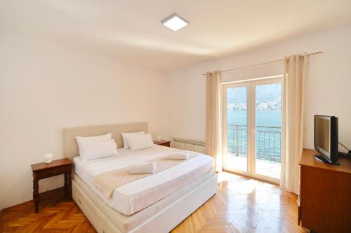 1 dormitorio con 1 cama, TV y ventana en House 44 SEAFRONT APARTMENTS, en Kotor