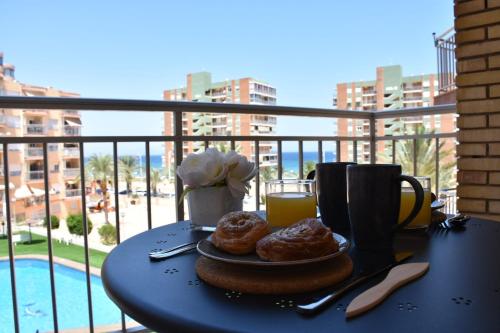 una mesa con un plato de donuts y un vaso de zumo de naranja en Myflats Deluxe Seafront, en Arenales del Sol