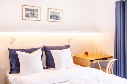 a bed with white sheets and blue pillows next to a table at Hørby Færgekro in Holbæk