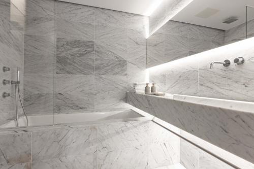a white bathroom with a tub and a shower at La Suite West - Hyde Park in London