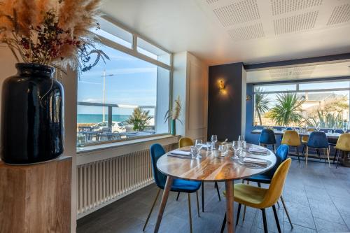 a dining room with a table and chairs and a large window at Hôtel des Isles in Barneville-Carteret