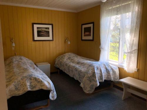 1 dormitorio con 2 camas y ventana en Holandsøya Gård 