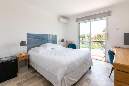 sypialnia z dużym białym łóżkiem i balkonem w obiekcie HOTEL LA QUIETUDE w mieście Les Issambres