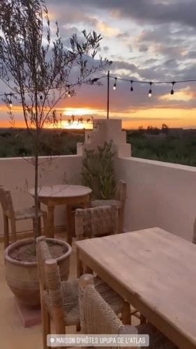 a patio with tables and chairs with a sunset in the background at Upupa de l’Atlas in Marrakech