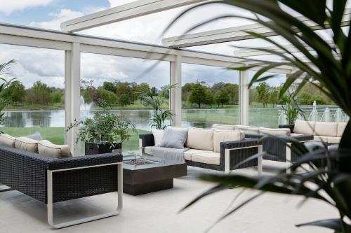a conservatory with white furniture and large windows at The K Club in Straffan