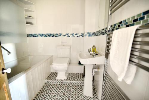 a white bathroom with a toilet and a sink at 1 Cobb View in Lyme Regis