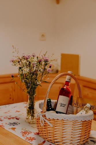 a basket with two bottles of wine and a vase of flowers at Almhaus Kochjosel in Garanas