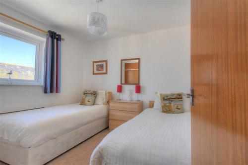 a bedroom with two beds and a window at 4 Bay View Court in Lyme Regis