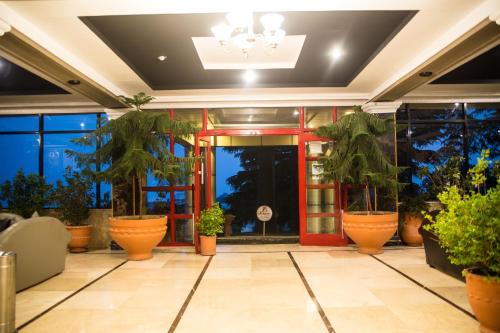 a lobby with potted plants and a red door at Metropole Hotel in Murree