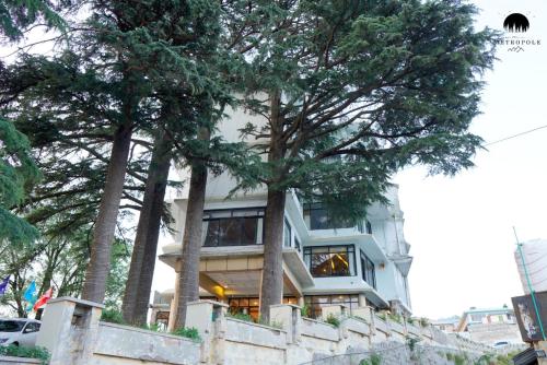 a white house with trees in front of it at Metropole Hotel in Murree