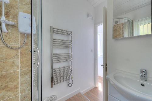 a white bathroom with a sink and a shower at The Beach Hut in Lyme Regis