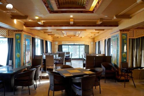 a dining room with tables and chairs and windows at Metropole Hotel in Murree