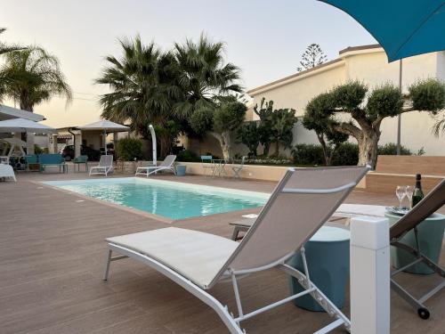 a pool with chairs and a table and an umbrella at Xenìa - Villa con Piscina Privata in Agrigento