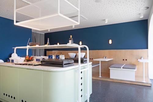 une cuisine avec des murs bleus et un comptoir blanc dans l'établissement MEININGER Hotel Bremen Hauptbahnhof, à Brême