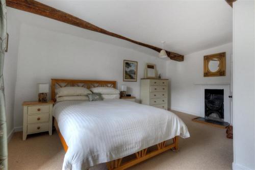 1 dormitorio con cama blanca y chimenea en Hamilton House, en Lyme Regis