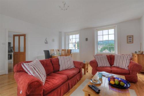 a living room with two red couches and a table at Rooftops in Lyme Regis