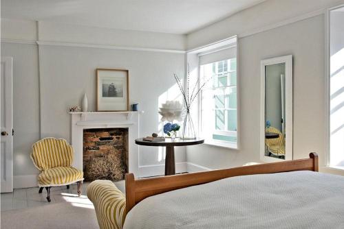 1 dormitorio con 1 cama, chimenea y silla en The Arched House, en Lyme Regis