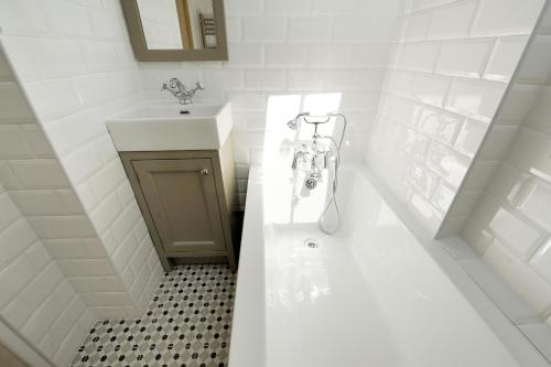 a white bathroom with a tub and a sink at The Lodge in Lyme Regis