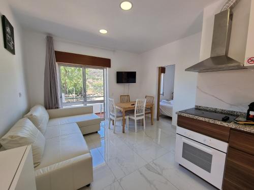 a living room with a white couch and a kitchen at AAA Apartments in Albufeira