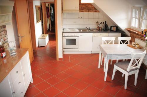 a kitchen with a red tile floor and a table and chairs at Forsthof Nunkirchen in Wadern