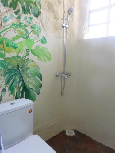 a bathroom with a toilet with a painting on the wall at Aloepark Art Hotel in Naivasha