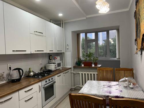 a kitchen with white cabinets and a table with chairs at Downtown Homestay in Bishkek