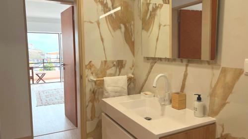 uma casa de banho com um lavatório e um espelho em Apartamento Frente Mar Praia da Areia Branca em Praia da Areia Branca