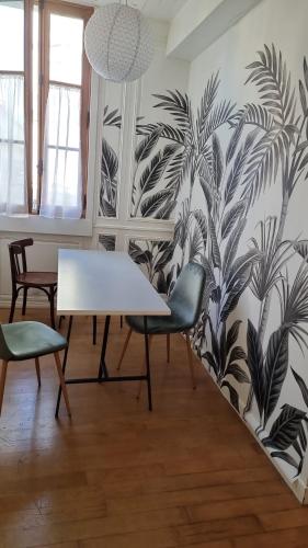 - une table et des chaises dans une pièce ornée d'une fresque murale dans l'établissement A 2 PAS DU PARLEMENT - 55M2 - 2 CHAMBRES, à Rennes