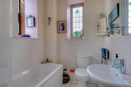 a bathroom with a tub and a toilet and a sink at 6 Coram Tower in Lyme Regis