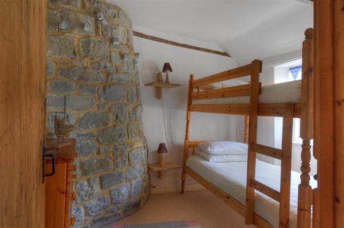 a bedroom with two bunk beds and a stone wall at Ivy Cottage in Lyme Regis