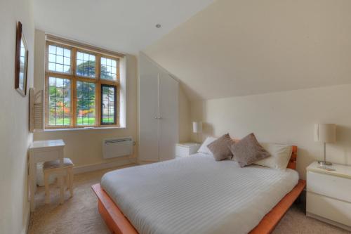 a white bedroom with a bed and a window at 7 Coram Tower in Lyme Regis