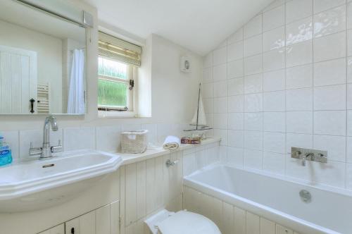 a white bathroom with a tub and a sink at Charm Cottage in Charmouth