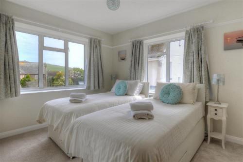 two beds in a bedroom with two windows at 2 Grange Villas in Charmouth
