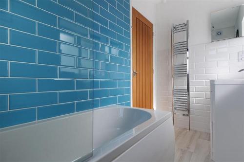 a blue tiled bathroom with a tub in it at 2 Grange Villas in Charmouth
