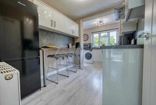 a kitchen with a counter and stools in it at Elegant 5 Bed House - Sleeps 9, Central Solihull, NEC, JLR, HS2, Resorts World, Airport Business and Leisure Stays, in Solihull