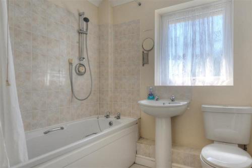 a bathroom with a tub and a toilet and a sink at 4 Riverside Cottages in Charmouth