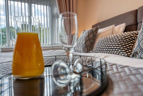 a table with two wine glasses on top of a bed at Elegant 5 Bed House - Sleeps 9, Central Solihull, NEC, JLR, HS2, Resorts World, Airport Business and Leisure Stays, in Solihull