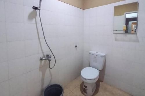 a white bathroom with a toilet and a shower at Graha HT Sumantri Mitra RedDoorz in Tasikmalaya