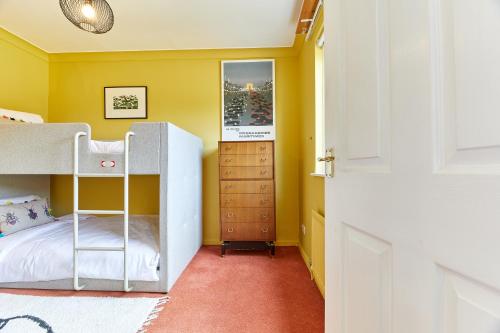 a bedroom with yellow walls and a bunk bed at Xanadu: Stylish Family Home by the Pub and Beach in Beadnell