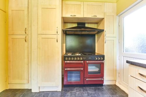 a red stove in a kitchen with a window at Xanadu: Stylish Family Home by the Pub and Beach in Beadnell
