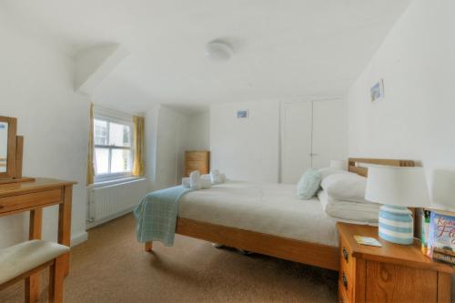 ein Schlafzimmer mit einem Bett und einem Tisch mit einer Lampe in der Unterkunft Monmouth Cottage in Lyme Regis