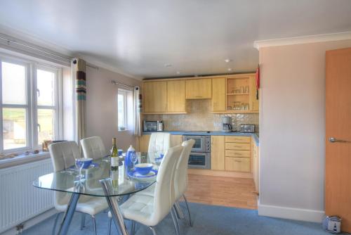 a kitchen with a glass table and white chairs at 9 Maritime House in West Bay