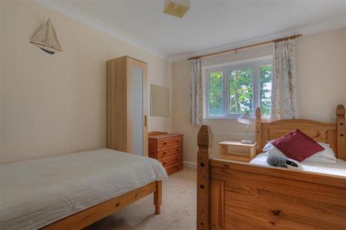 - une chambre avec un lit en bois et une fenêtre dans l'établissement 3 Riverside Cottages, à Charmouth