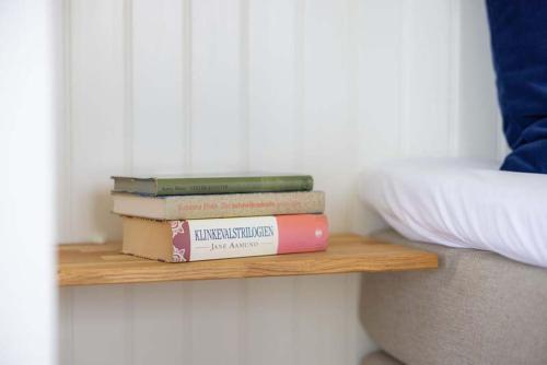 a stack of books sitting on a wooden shelf at Hørby Færgekro in Holbæk