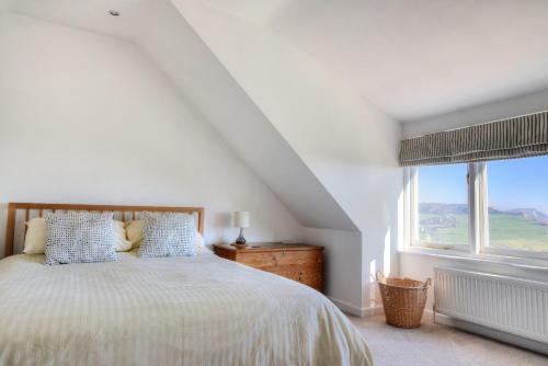a white bedroom with a bed and a window at Pendower in Charmouth