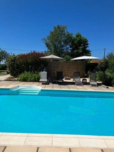 - une piscine avec 2 chaises longues et des parasols dans l'établissement Fleurs sauvages a Rebeuse NEW HOSTS Full of nature, à Corgnac-sur-lʼIsle
